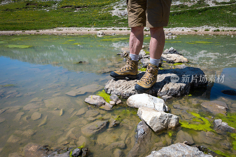 男人的特写跨越一个池塘，而徒步旅行周围的Tre Cime di Lavaredo在白云石，欧洲阿尔卑斯，意大利